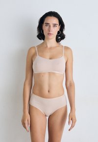 Naadloze natuurlijkkleurige bralette met dunne bandjes, gecombineerd met bijpassende hooggewrongen onderbroek. Zachte, rekbare stof met een gladde textuur.