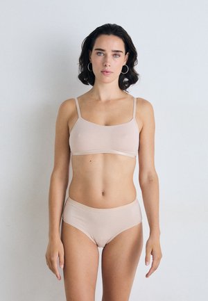 Nude seamless bralette with thin straps paired with high-waisted matching underwear. Soft, stretchy fabric with a smooth texture.