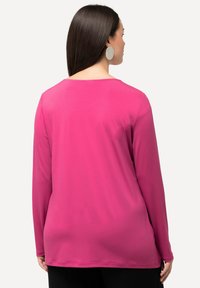 Maglietta rosa a maniche lunghe con scollo rotondo e una texture liscia e elastica. Presenta una vestibilità rilassata e dettagli di cucitura minimi.