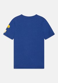 Camiseta de algodón azul con cuello redondo y mangas cortas, con un logo de baloncesto bordado en el hombro izquierdo.