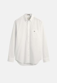 Bílá košile na knoflíky, měkká bavlněná látka, dlouhé rukávy, špičatý límeček, náprsní kapsa, nenápadný detail loga na kapse, zakřivený spodní lem.