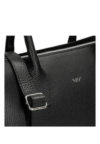 Borsa in pelle nera con superficie testurizzata, hardware in argento e chiusura con zip. La tracolla include un dettaglio con fibbia in metallo.