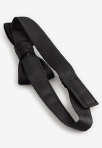 Schwarze Fliege mit einem strukturierten Stoffmittelteil und glatten Satinbändern. Sie verfügt über einen Klettverschluss zur sicheren Befestigung um den Hals.