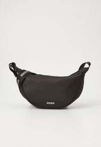 Černá nylonová taška přes pás s oblým tvarem, zdobená bílým logem "HUGO" a nastavitelného popruhu pro různé možnosti nošení.