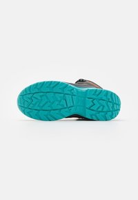Suola di scarpa sportiva con un design testurizzato. Presenta una parte superiore nera, una suola color turchese brillante e accenti arancioni vicino ai lacci.