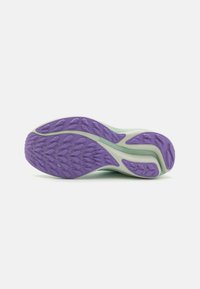Semelle d'une sneaker avec une tige vert menthe clair et une semelle extérieure en caoutchouc violette contrastante, texturée avec un motif de vagues pour une meilleure adhérence.