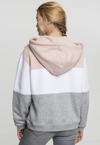 Hettegenser med fargeblokkeringsdesign i lys rosa, hvit og grå. Laget av mykt stoff, har kengurulomme og ribbestrikkede mansjetter.