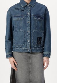 Chaqueta vaquera con cuello, color azul, bolsillos frontales, botones a presión y detalles bordados en el pecho y las mangas.