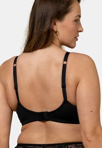 Soutien-gorge noir avec bretelles ajustables, fermeture à crochet et œil, tissu lisse et détails de couture subtils ; conçu pour le confort et le soutien.