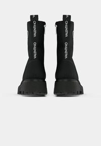 Czarne ankle boots z gładką cholewką, zamkiem błyskawicznym, masywną platformą i bocznym logo z napisem "VALENTINO" w kolorze białym.