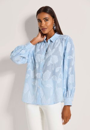 Light blue floral patterned shirt with a collared neckline, button closure, and long, puffed sleeves. Made of lightweight fabric.