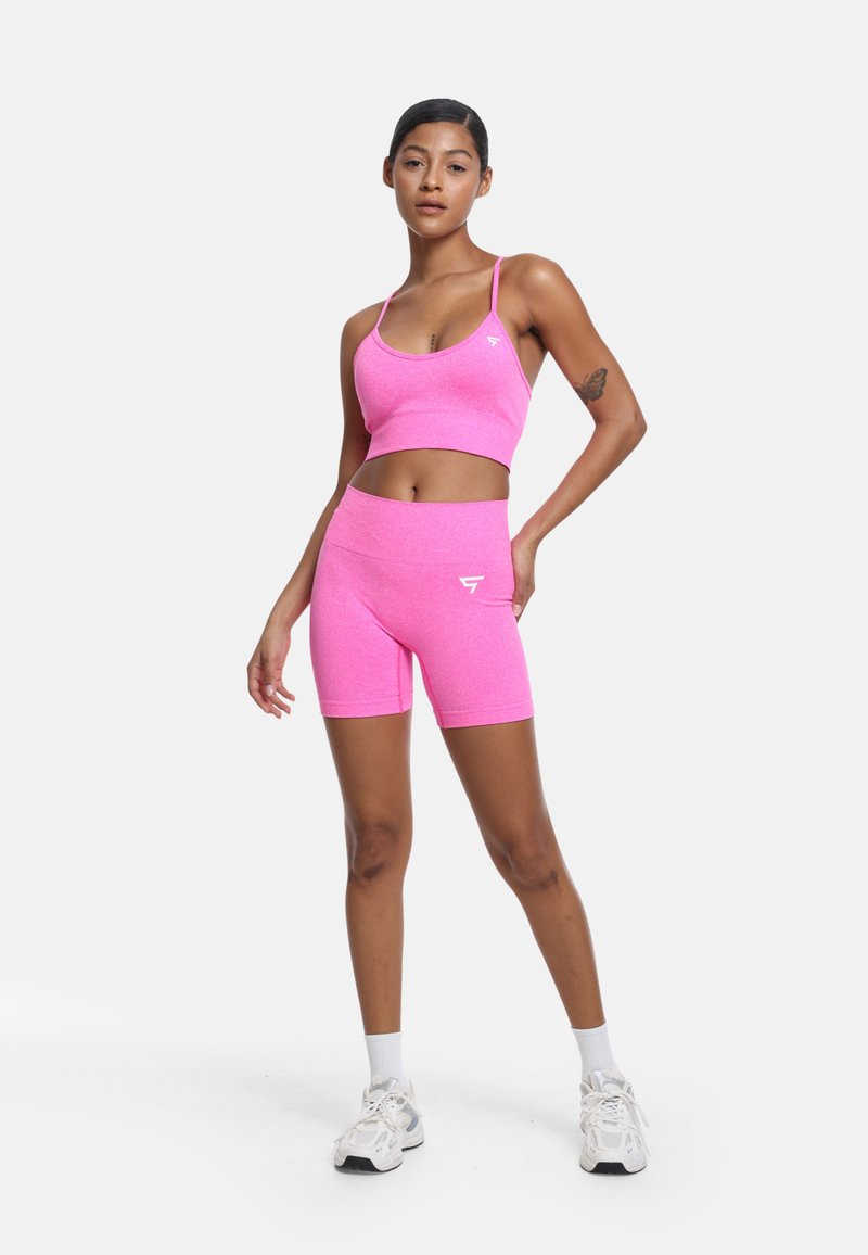 Ljusrosa sportbh och matchande högmidjade shorts, gjorda av ett strukturerat stretchmaterial. Har en liten vit logotyp på toppen.