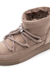 Beżowe zamszowe tenisówki wysokie z grubymi, teksturowanymi sznurówkami i miękkim, futrzanym wnętrzem. Posiadają gumową podeszwę oraz metalowe akcenty.
