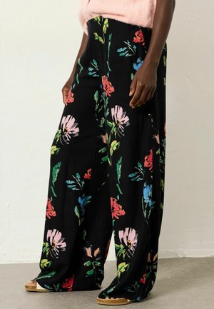 Black floral pants featuring a textured fabric with large multicolored flower patterns. Wide-leg design with a loose fit and elastic waistband.