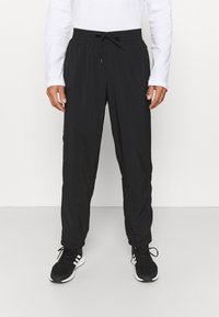 Schwarze Sporthose aus leichtem Material, mit einem elastischen Bund und einem Kordelzug, elastischen Bündchen und seitlichen Taschen.