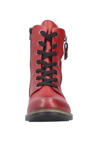 Bottine en cuir rouge avec des lacets noirs, fermeture zippée sur le côté et une semelle texturée. Présente des œillets en argent et un bout arrondi.