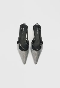 Melnā ādas kurpes ar norādītu purngalu un atvērtu papēdi, dekorētas ar sudraba rhinestones. Tām ir plānas siksnas un gluda iekšpuse.