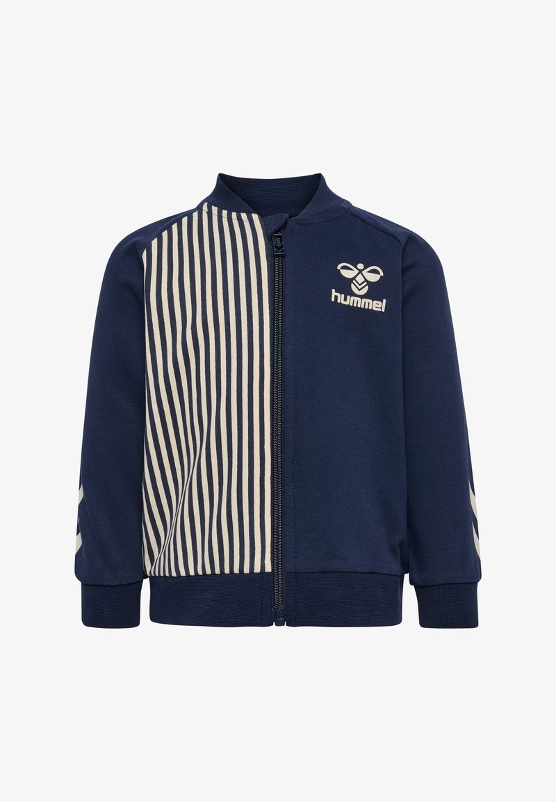 Veste zippée marine avec des rayures crèmes verticales d'un côté, des poignets côtelés et un logo sur la poitrine. Fabriquée en matériau doux et extensible.