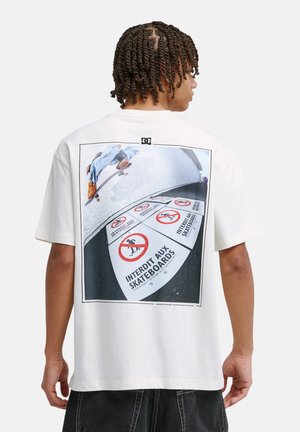 Weißes Baumwoll-T-Shirt mit einem Rückendruck eines Skateboarders und mehreren Verbotsschildern. Lockerer Schnitt, kurze Ärmel und Rundhalsausschnitt.