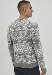 Grå strikket sweater med hvide snefnug- og rensdyrmønstre, rund hals og ribkant ved ærmer og kant.