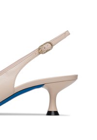 Scarpa slingback in pelle beige con tacco curvo, accentatura blu e fibbia dorata adornata con piccole pietre trasparenti. Texture liscia.