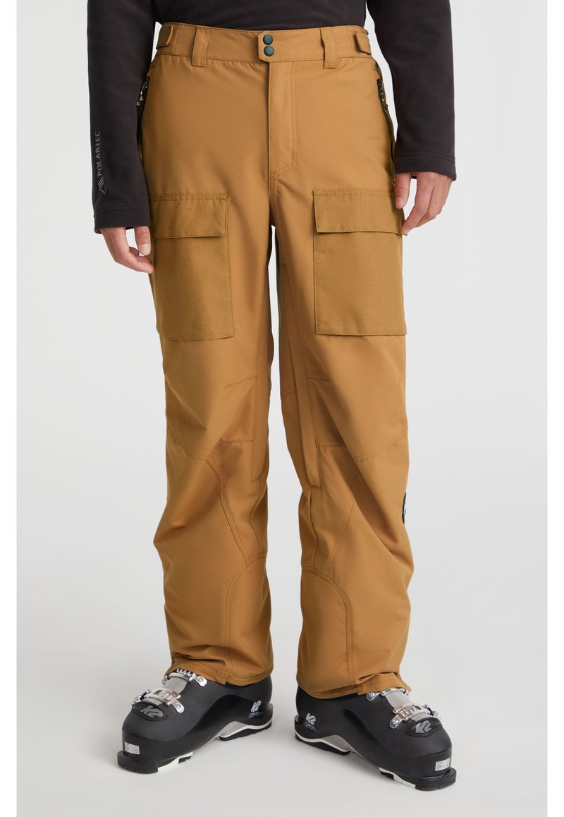 Cargo-Skipants aus braunem Material mit glatter Textur. Verfügt über zwei große Fronttaschen und einen figurbetonten Bund. Getragen mit schwarzen Skischuhen.