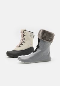 Bottes d'hiver en tissu gris flexible avec un doux bord en fourrure grise (à gauche) et en suede beige avec semelle en caoutchouc noir et lacets roses (à droite).