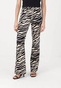 Black and white zebra print flared pants, elastic waistband, lightweight fabric, with a smooth texture. Combined with black heeled sandals.