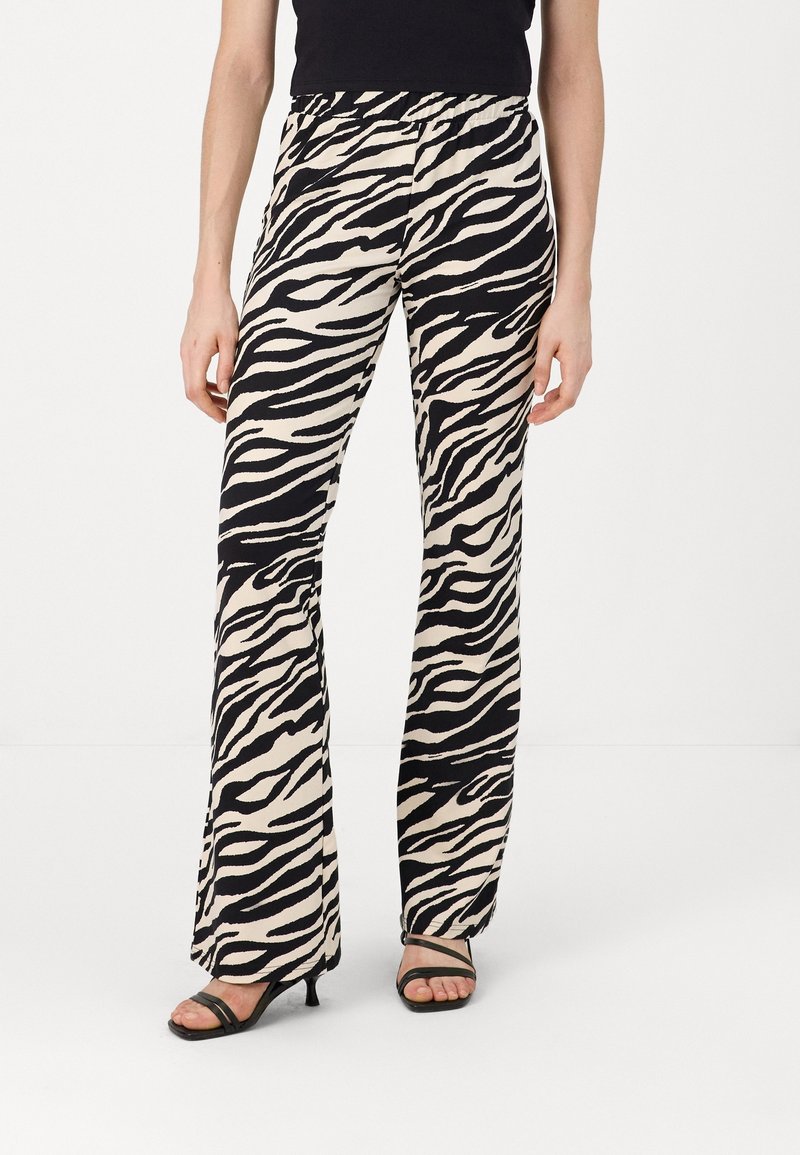 Black and white zebra print flared pants, elastic waistband, lightweight fabric, with a smooth texture. Combined with black heeled sandals.