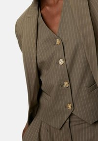 Oliwkowo-zielony garnitur w prążki z dopasowaną marynarką i dopasowaną kamizelką. Charakteryzuje się pięcioma jasnymi guzikami i gładką fakturą.