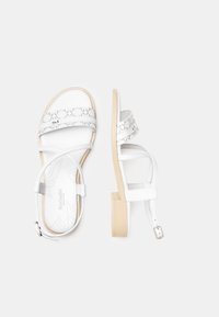 Sandales blanches en cuir, avec des brides croisées, un motif embossé et un petit talon bloc. Sangle de cheville avec détail de boucle incluse.