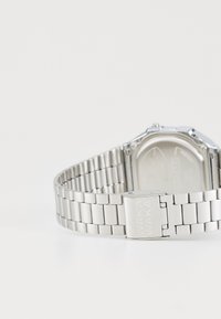 Montre en métal argenté avec un design de bracelet à maillons, dotée d'un boîtier rectangulaire et d'un fermoir gravé du texte "WAKA WAKA."