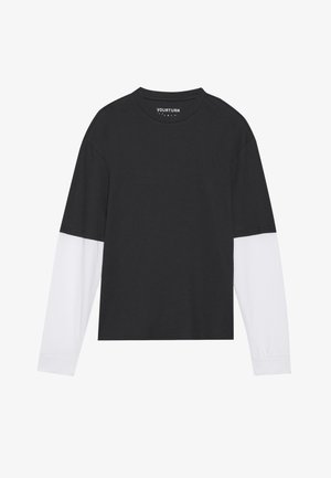 Black long-sleeve top with white sleeves, ribbed texture, round neck, and a cropped design. Brand label visible inside the neckline.