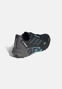 Chaussure de trail Adidas Terrex GTX 300 noire et grise avec des accents turquoise et une semelle texturée, vue de côté et de dos.