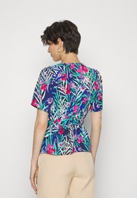 Blusa de manga curta em azul marinho com padrões florais vibrantes em rosa e verde, apresentando uma cintura ajustada e um corte relaxado.