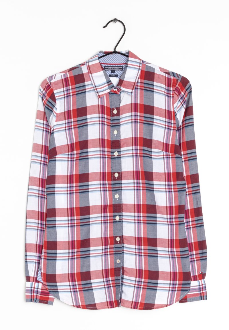 Chemise à carreaux rouges, blancs et gris, à manches longues, boutonnée, sur un cintre noir sur fond blanc.