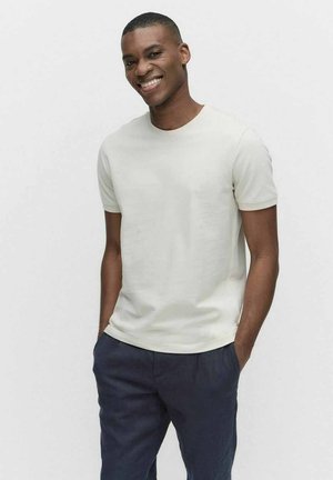 Lichtbeige korte mouw t-shirt van zachte katoen, met een ronde halslijn en een aansluitende pasvorm, gecombineerd met marineblauwe broek.