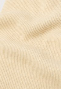 Tejhez hasonló, krém színű, bordázott anyag, amely puha tapintású, és szembetűnő függőleges vonalakkal rendelkezik, amelyek finom mintát alkotnak.