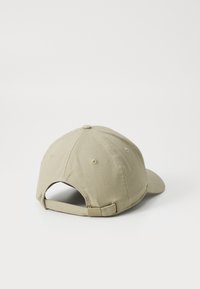 Beige puuvillane kork kaarjaga sirdiga, reguleeritava rihmaga taga ja ventilatsiooniaukudega. Sile tekstuur ja lihtne disain.