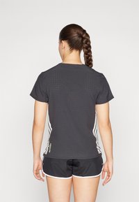 Mørkegrå sportstopp med kort erme og perforert tekstur, hvite side-striper og grønn "ADIZERO"-branding nederst til venstre. Svarte shorts med hvit trim.