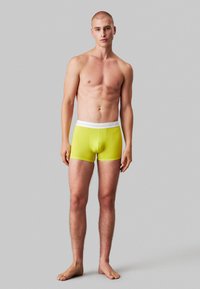Boxer briefs gialli brillanti con un elastico bianco in vita, caratterizzati da un design aderente e una texture liscia.