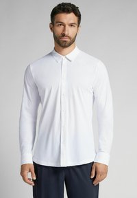 Witte long-sleeve shirt met een button-down kraag, een gladde textuur en een getailleerd ontwerp. Te zien met donkere broeken, minimale details.