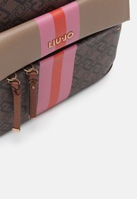 Brun mønstret håndtaske med lyserøde, orange og beige accenter, med detaljer i guld og lynlåse, lavet af syntetisk materiale.
