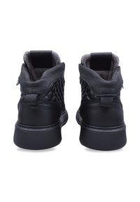 Czarne skórzane sneakersy z pikowaną teksturą na pięcie, gładkim wykończeniem i szarym materiałem wyściółki wewnątrz. Solidna gumowa podeszwa zapewniająca dobrą przyczepność.