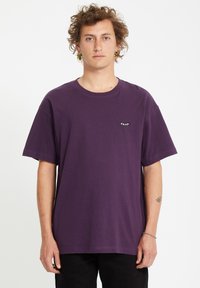 Paarse katoenen T-shirt met een ronde hals en korte mouwen. Bevat een klein zwart logo op de linkerborst. Eenvoudig ontwerp, relaxte pasvorm.