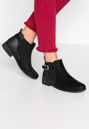 Schwarze Knöchelstiefel mit einem strukturierten schwarzen Einsatz, einer glatten Vorderseite und einem kleinen Absatz. Details umfassen eine Schnallenakzent an der Seite.