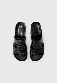 Sandale negre din patent, cu vârf deschis, două curele orizontale cu detalii decupate și un toc mic bloc. Textură netedă.