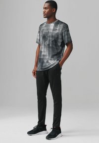 Gray geometric patterned t-shirt paired with black athletic pants and black sneakers, featuring a relaxed fit and smooth texture.