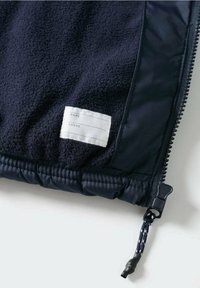 Merivärvi fleecetakki pehmea tekstuuriga, elastse äärise ja lukuga. Omab valget kangast sildi, kuhu saab kirjutada nime ja telefoninumbri.