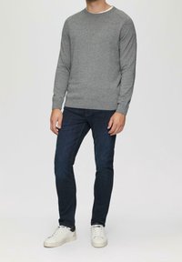 Szary dzianinowy sweter z okrągłym dekoltem, noszony na ciemnoniebieskich dżinsach, w parze z białymi tenisówkami. Tkanina wygląda na miękką i o fakturze.